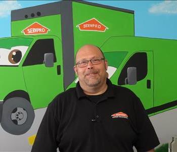 Male SERVPRO employee standing in front of green SERVPRO truck