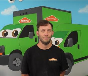 Male SERVPRO employee standing in front of green SERVPRO truck.