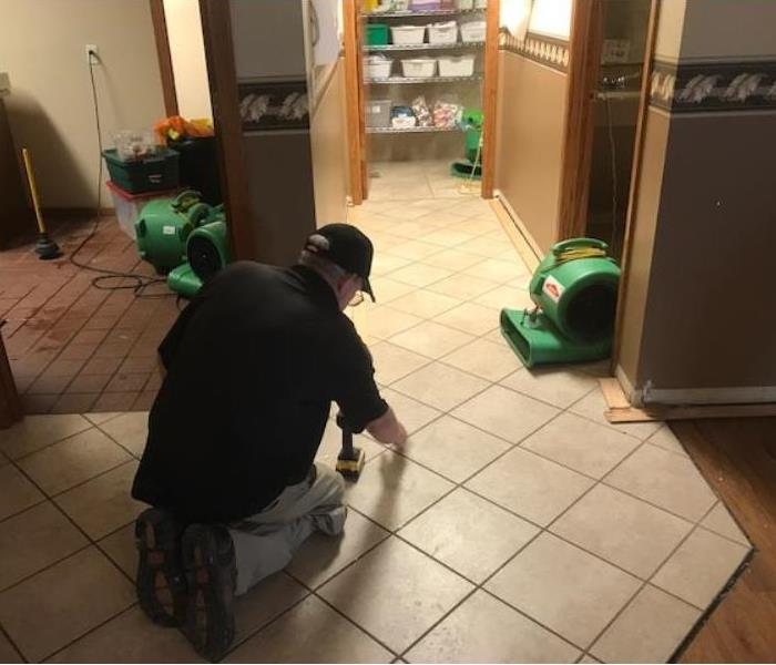 SERVPRO employee working to restore water damage on tile floor. 