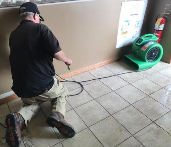 SERVPRO production crew mitigating water damage on tile floor. 